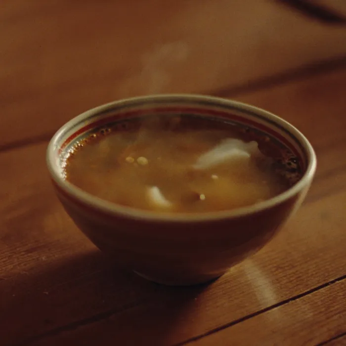 Un cuenco de sopa caliente humeando sobre una mesa de madera.